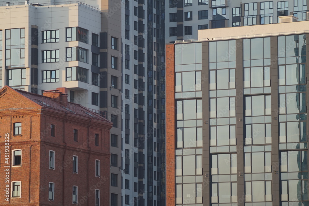 Photo of a part of the facades of modern buildings. Urban landscape at sunset. A pile of glass, concrete and brick. Photo of a part of the facades of modern buildings. Urban landscape at sunset. A pile of glass, concrete and brick.