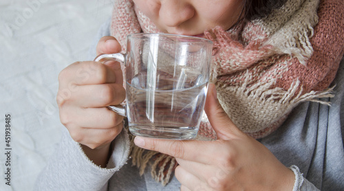 A cold woman drinks hot water.