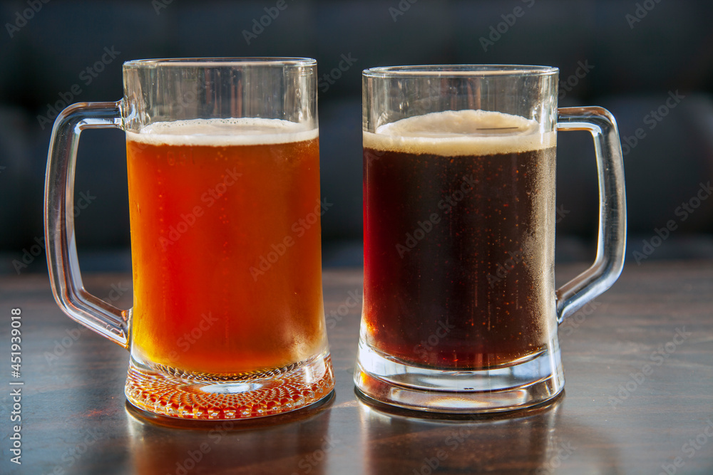 two large mugs of dark and light beer two large mugs of dark and light beer