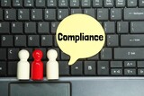 laptop keyboard, peg doll, conversation box with the word Compliance