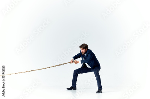 a man in a suit pulls the rope career office light background