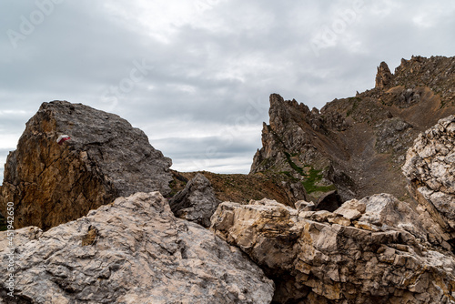 high mountain scenery with rocks, stone with trail mark and cloudy sky in Dolomites