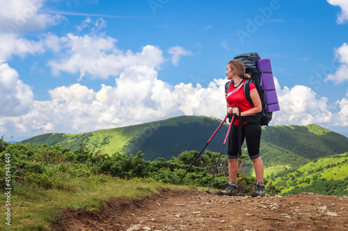 Summer hike in mountain. The young girl is walking along the trail with a backpack. Fitness and healthy lifestyle.