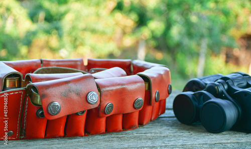 Cartridge belt with a leather belt for hunting. knifeand sporting cartridges for a smooth-bore shotgun.Old hunting cartridges and bandoleer on a wooden  photo