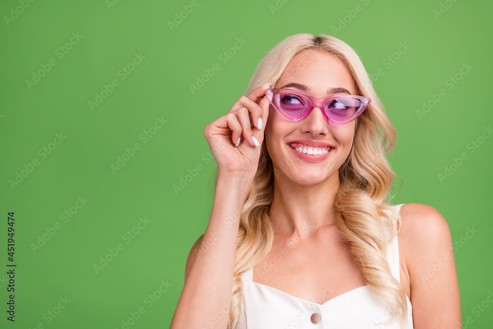 Portrait of young good looking smiling female in pink glasses look copyspace dreaming isolated on green color background Portrait of young good looking smiling female in pink glasses look copyspace dreaming isolated on green color background