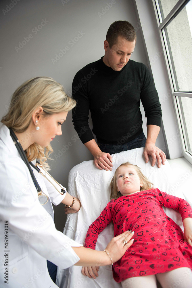 Fototapeta premium Father with girl being examined by female pediatrician in clinic