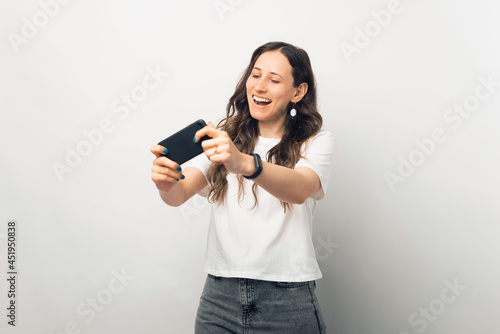 Young woman is having fun while playing at her phone in a studio.