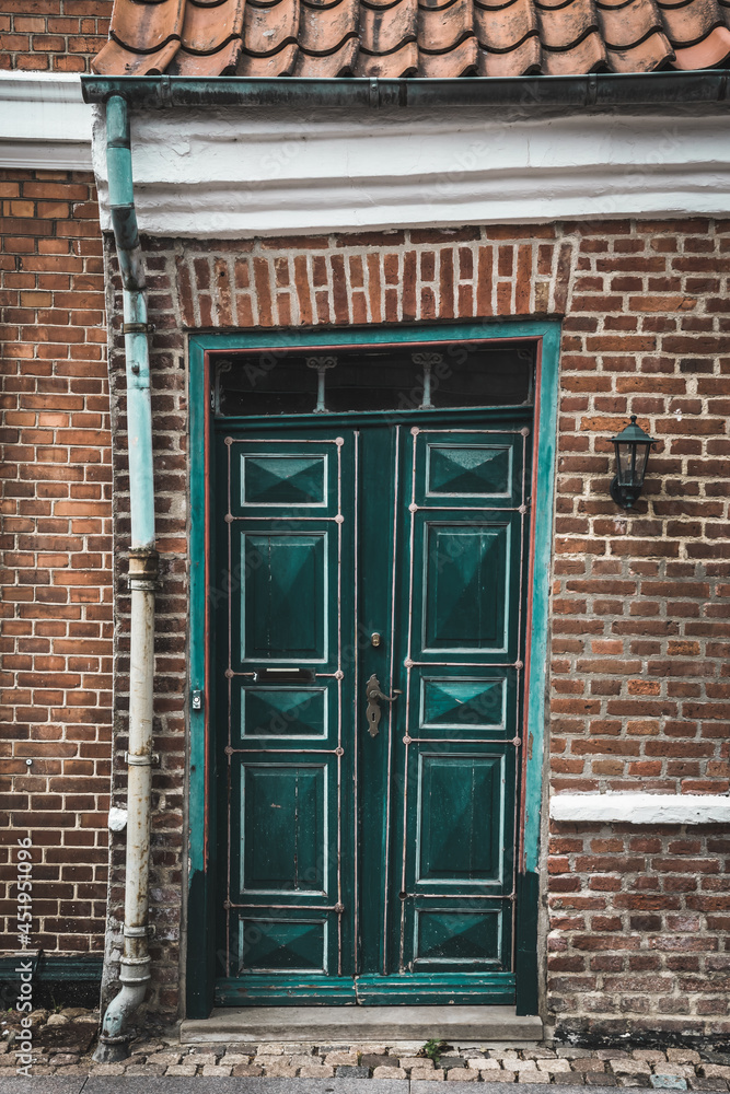 Old green warped crooked wooden door on a brick building Old green warped crooked wooden door on a brick building