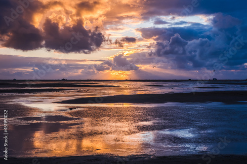 Sunset on a cloudy colorful sky over the North Sea in Denmark with high reflection in the water photo