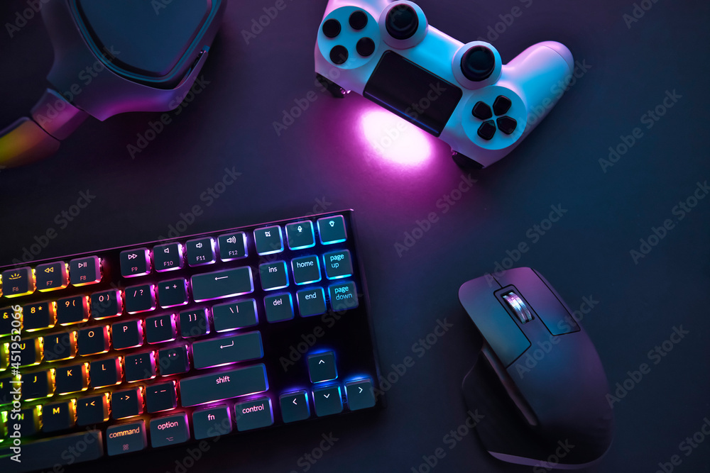 Top down view of various gaming accessories laying on table. Colorful illuminated devices. - obrazy, fototapety, plakaty 