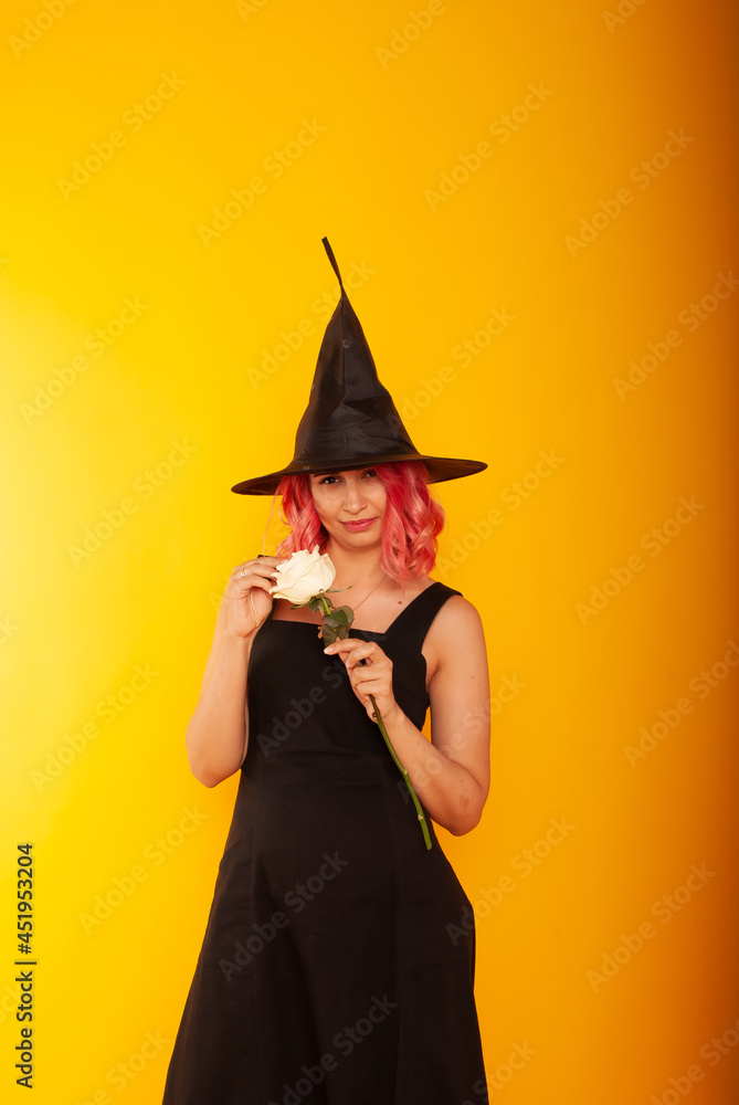 a woman witch with a rose in her hands smashes it for halloween while pronouncing a spell. Feast of evil spirits. Witch, place for text