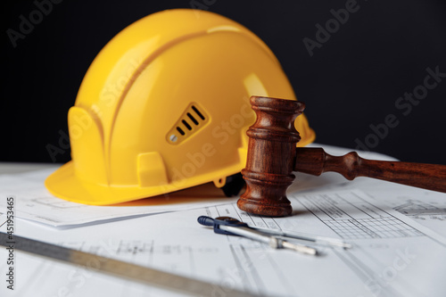 Wooden gavel with yellow helmet. Construction law concept