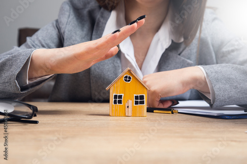 young woman hands protecting a model of house