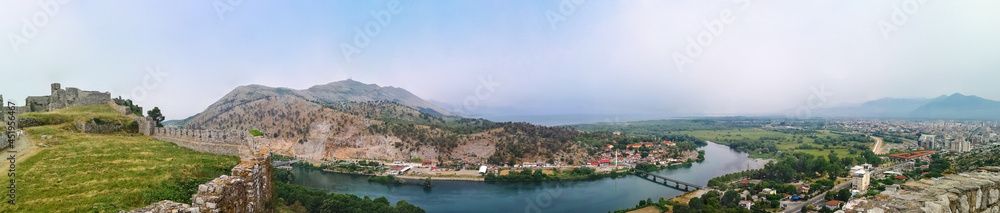 Panorama of the Buna river valley - view from the wall of the Shkoder castle (Albania). Beautiful widescreen landscape with the ruins of an ancient fortress, mountains, plain, river and city