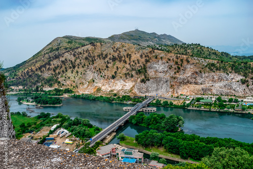 Amazing landscape of the Buna river with the Ura Bunes Shkoder bridge - view from Rozafa castle. Beige mountains, green trees and dark turquoise water - a beautiful Albanian scenery photo