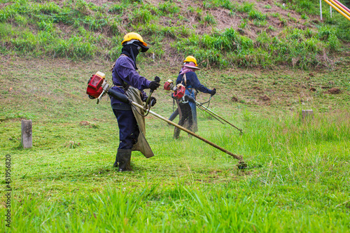 Female working wear protective clothing mows the lawn grass