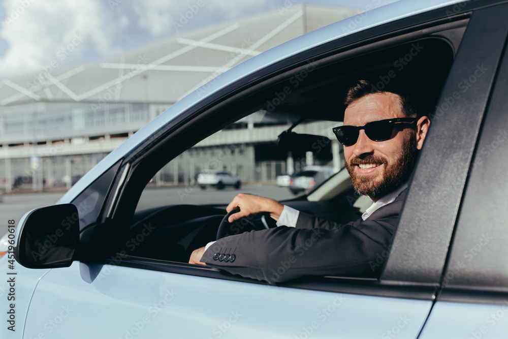 Businessman in black glasses sitting behind the wheel of a car Businessman in black glasses sitting behind the wheel of a car