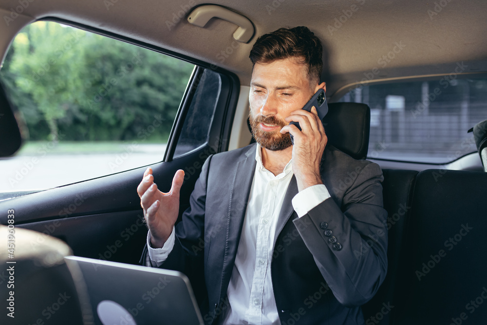 man talking on the phone sitting in the car working with a laptop man talking on the phone sitting in the car working with a laptop