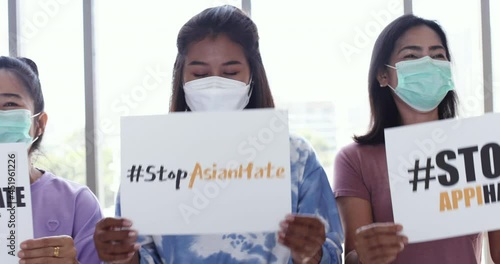 Group of diversity Asian women wearing protective face mask holding a paper with words during participants in Asian American Pacific Islanders rally marching protest to stop hate on AAPI citizen.