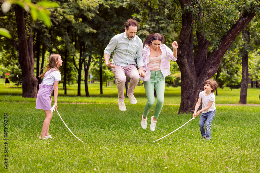 Photo of charming funky family dressed casual outfit playing jumping rope smiling outside urban city street Photo of charming funky family dressed casual outfit playing jumping rope smiling outside urban city street