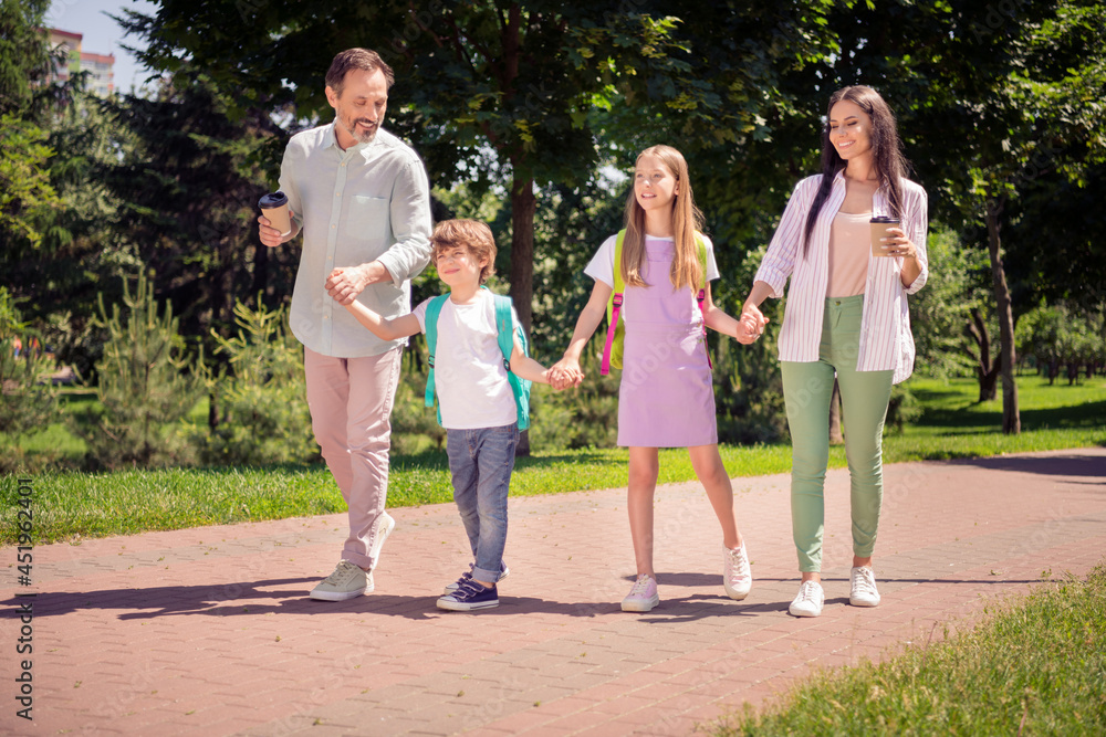 Photo of pretty sweet preteen boy girl mother father dressed casual outfit holding arms walking holding beverages outside city park Photo of pretty sweet preteen boy girl mother father dressed casual outfit holding arms walking holding beverages outside city park