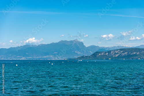 Lake Garda (Lago di Garda) and Italian Alps, mountain peak of Monte Pizzocolo, Adamello and Brenta Dolomites, headland of San Vigilio. Veneto, Lombardy and Trentino Alto Adige, Italy, Europe.