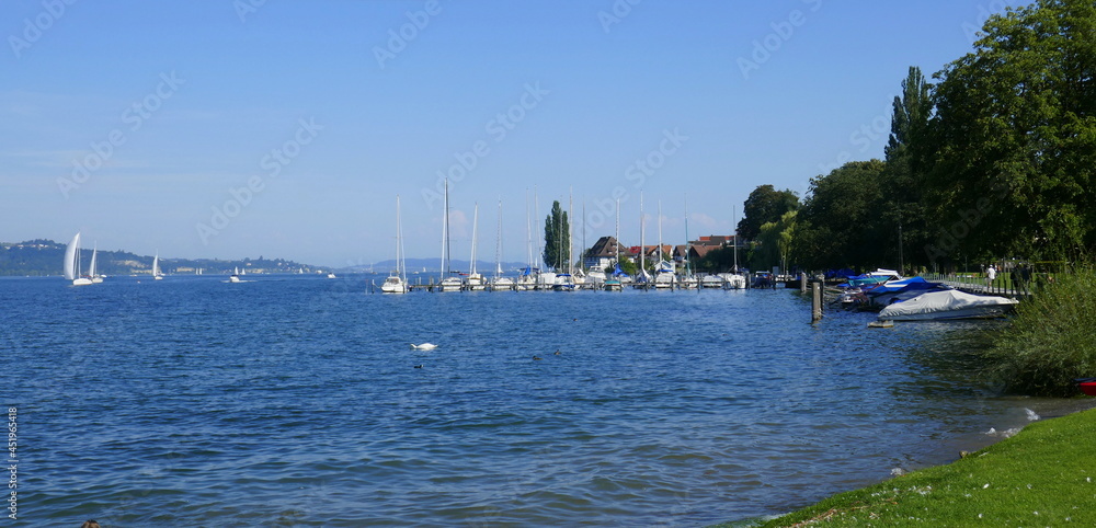 Hafen in Bodmann am Bodensee mit Booten und Schiffen und am Bildrande mit Personen