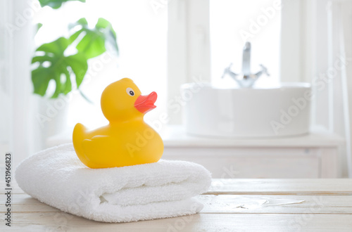 Fototapeta Towel and bath duck on table on blurred bathroom background
