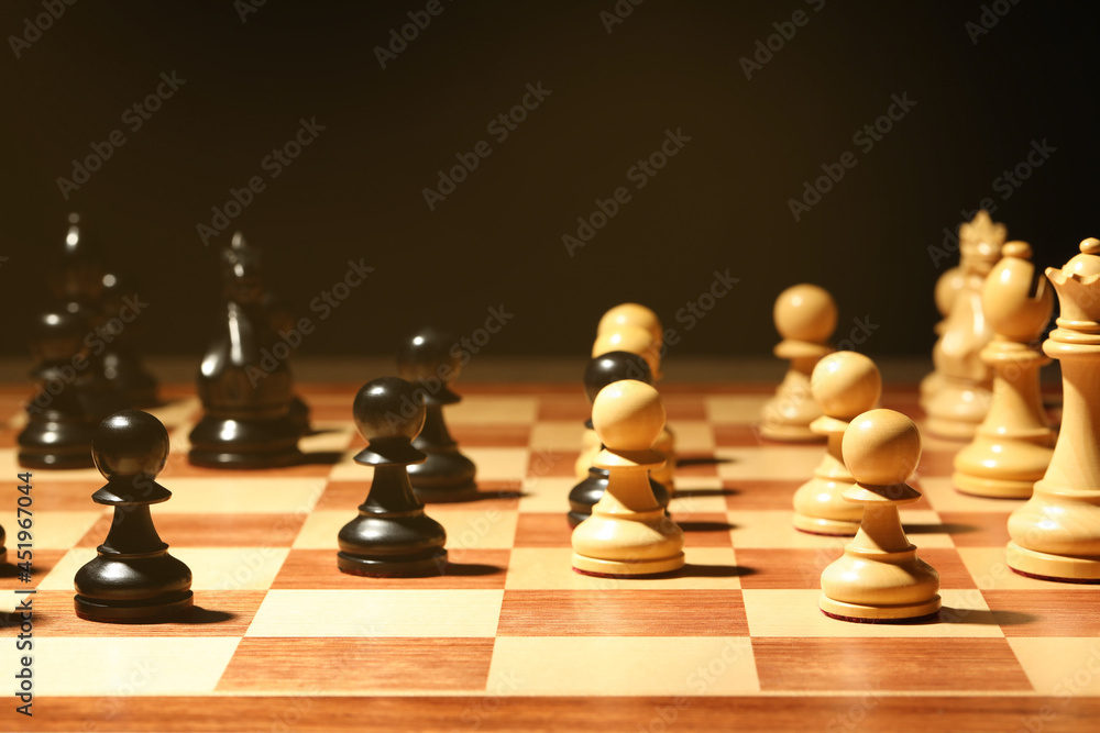 Chessboard with game pieces on black background Chessboard with game pieces on black background