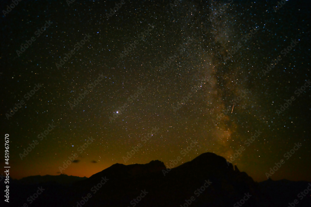 Starry sky with the Milky Way and shooting stars over the Swiss mountains 