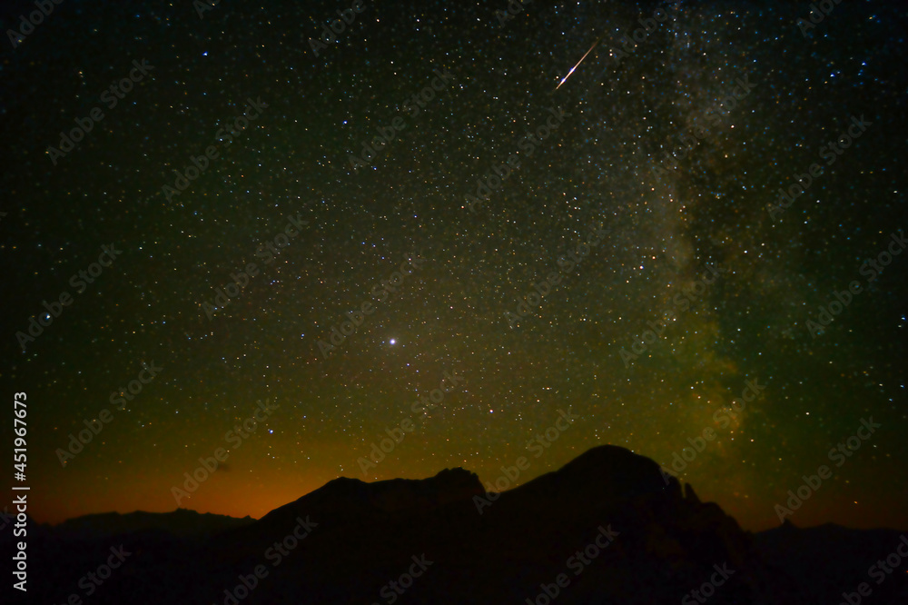 Starry sky with the Milky Way and shooting stars over the Swiss mountains 
