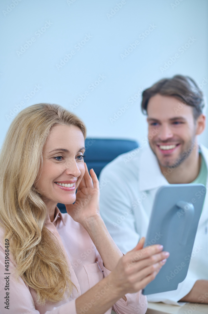 Smiling contented patient holding a handglass before her face Smiling contented patient holding a handglass before her face