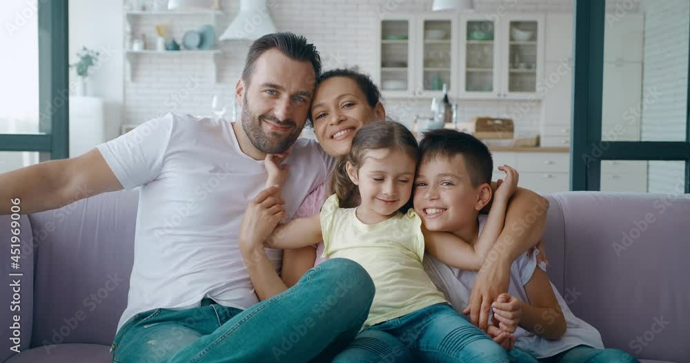 Smiling brother leaning to his younger sister.Portrait of lovely family resting on the sofa close to each other. Handsome mature father hugging his family. 4K video Smiling brother leaning to his younger sister.Portrait of lovely family resting on the sofa close to each other. Handsome mature father hugging his family. 4K video