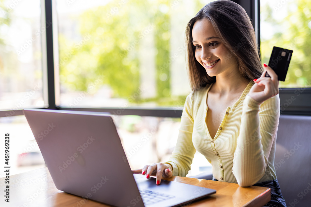 Close up of a happy woman hand buying online with a laptop and paying with a credit card Close up of a happy woman hand buying online with a laptop and paying with a credit card