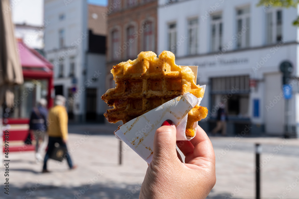 Fototapeta premium Eating of Belgian sugar waffles, street food in Bruges