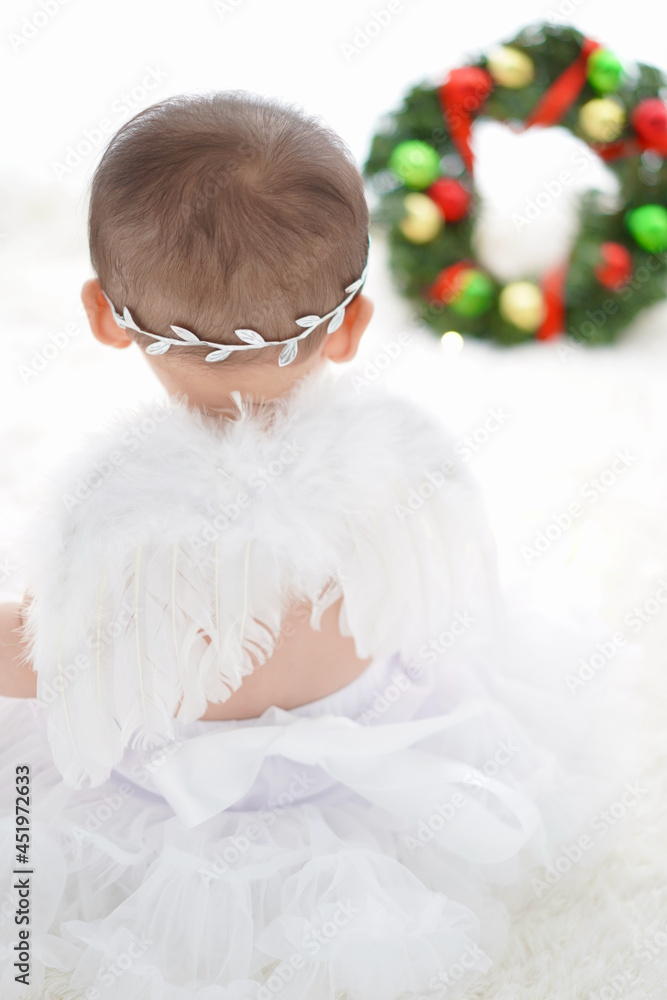 クリスマスリースを見つめる白い羽の赤ちゃん天使 クリスマスリースを見つめる白い羽の赤ちゃん天使
