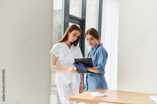 Two doctors in uniform standing indoors and working together