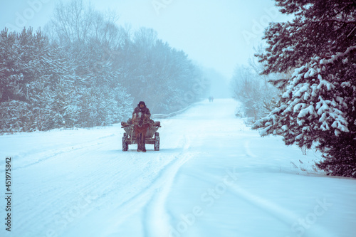 A man rides in a horse-drawn cart on the winter snowy road