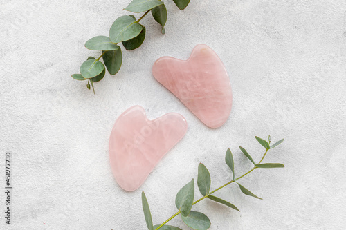 Rose quartz gua sha massage stone with green leaves photo