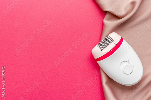 White epilator on soft silk. Hair removal and depilatory concept photo