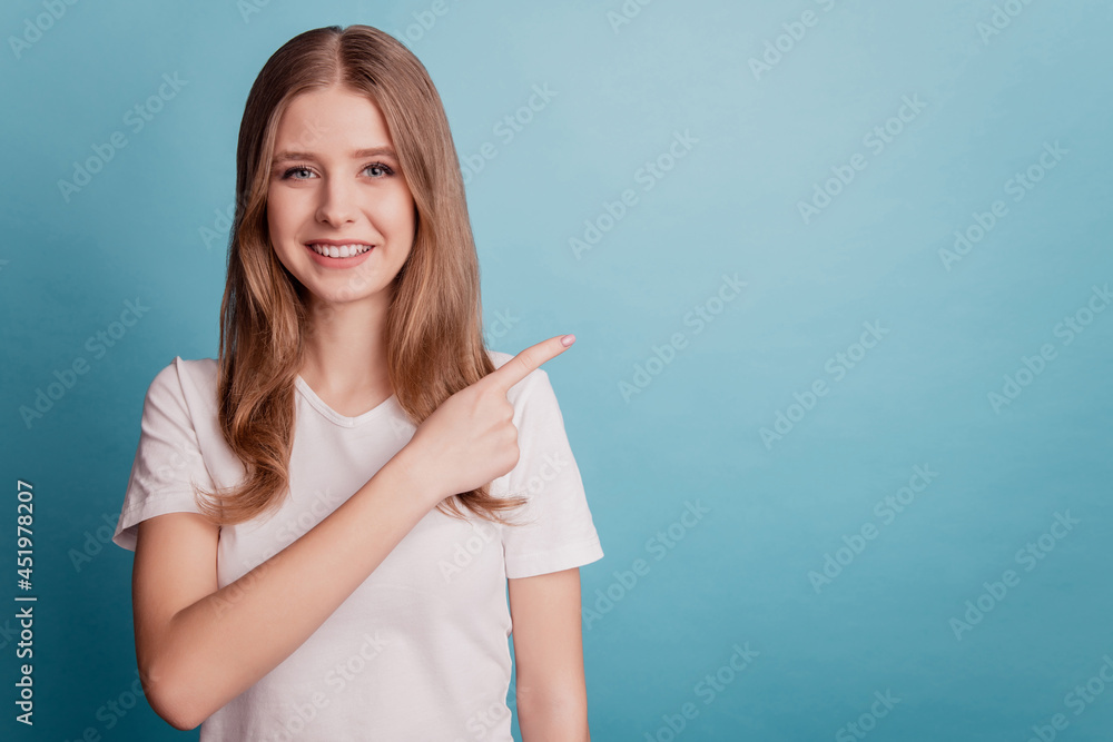 Portrait of cheerful promoter girl direct finger empty space demonstrate discount on blue background Portrait of cheerful promoter girl direct finger empty space demonstrate discount on blue background