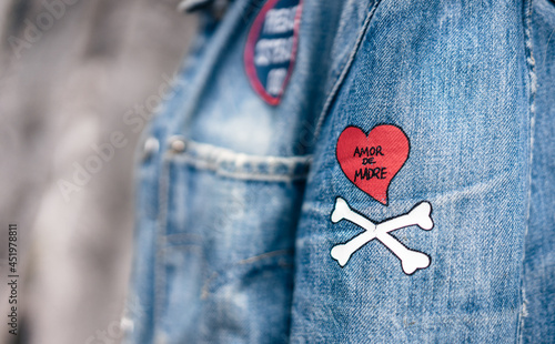 primer plano de detalle en cazadora vaquera con dibujo de Amor de madre, corazón y huesos. denim.