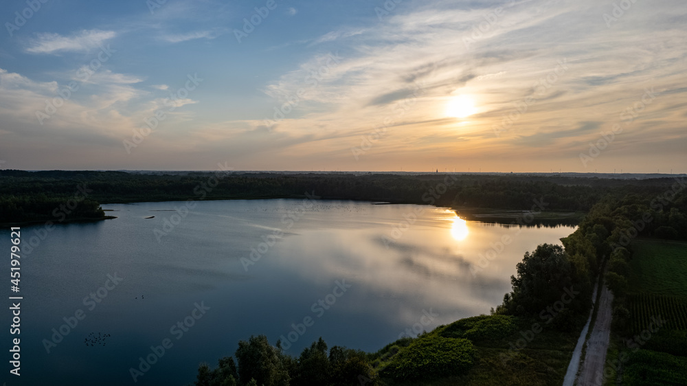Aerial view shot by a drone of a beautiful dramatic and colorful sunset at coast of the lake. Nature landscape. Nature in Europe. reflection, blue sky and yellow sunlight. landscape during sunrise or