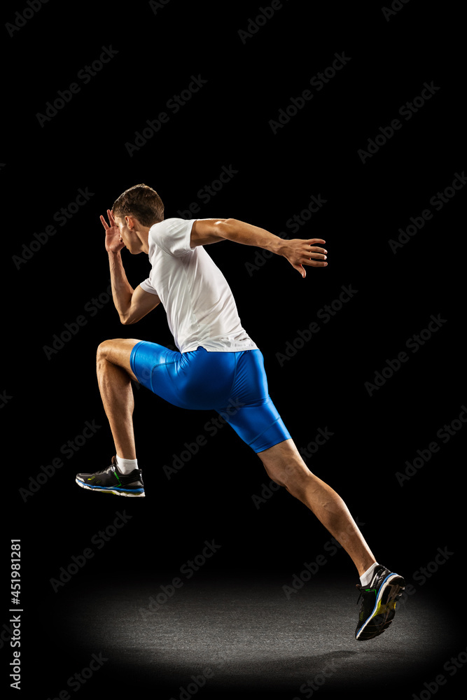 Static portrait muscular, sportive man, male athlete, runner training isolated on dark studio background with spotlight. Concept of action, motion, youth, healthy lifestyle.