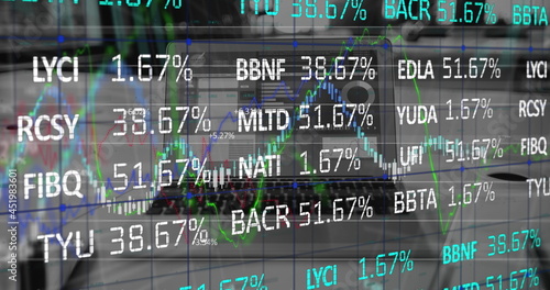 Digital composite image of stock market data processing against laptop on office desk