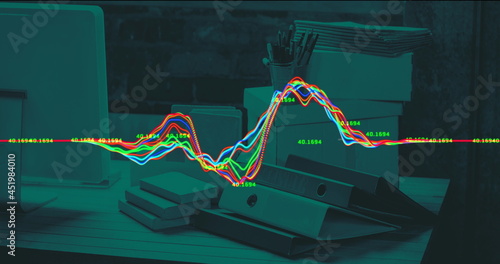 Image of financial data processing with fluctuating lines over office desk