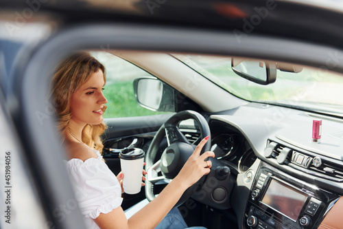 In front of steering wheel. Young woman in casual clothes is sitting in her car at daytime © standret