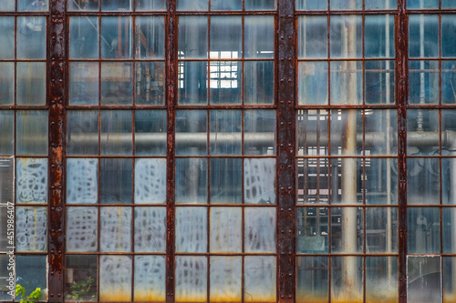 Old industrial pipes seen through grungy window panes