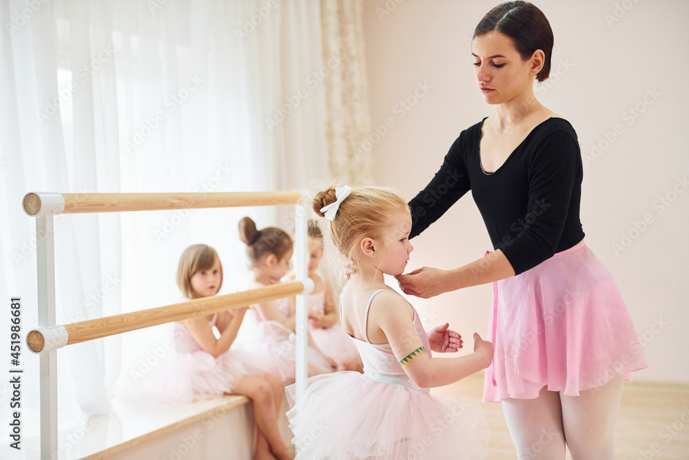 Fixing posture. Little ballerinas preparing for performance by practicing dance moves Fixing posture. Little ballerinas preparing for performance by practicing dance moves