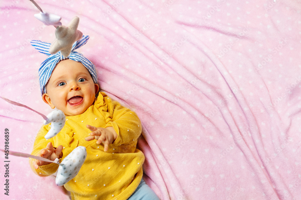 Fototapeta premium Baby girl laugh with mobile toys view from above